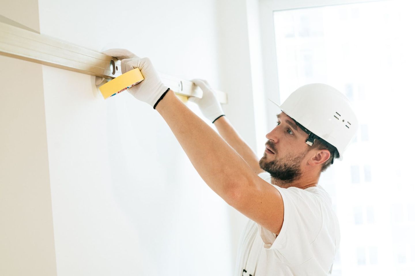 Handwerker setzt eine Wasserwaage an eine verputzte Wand an